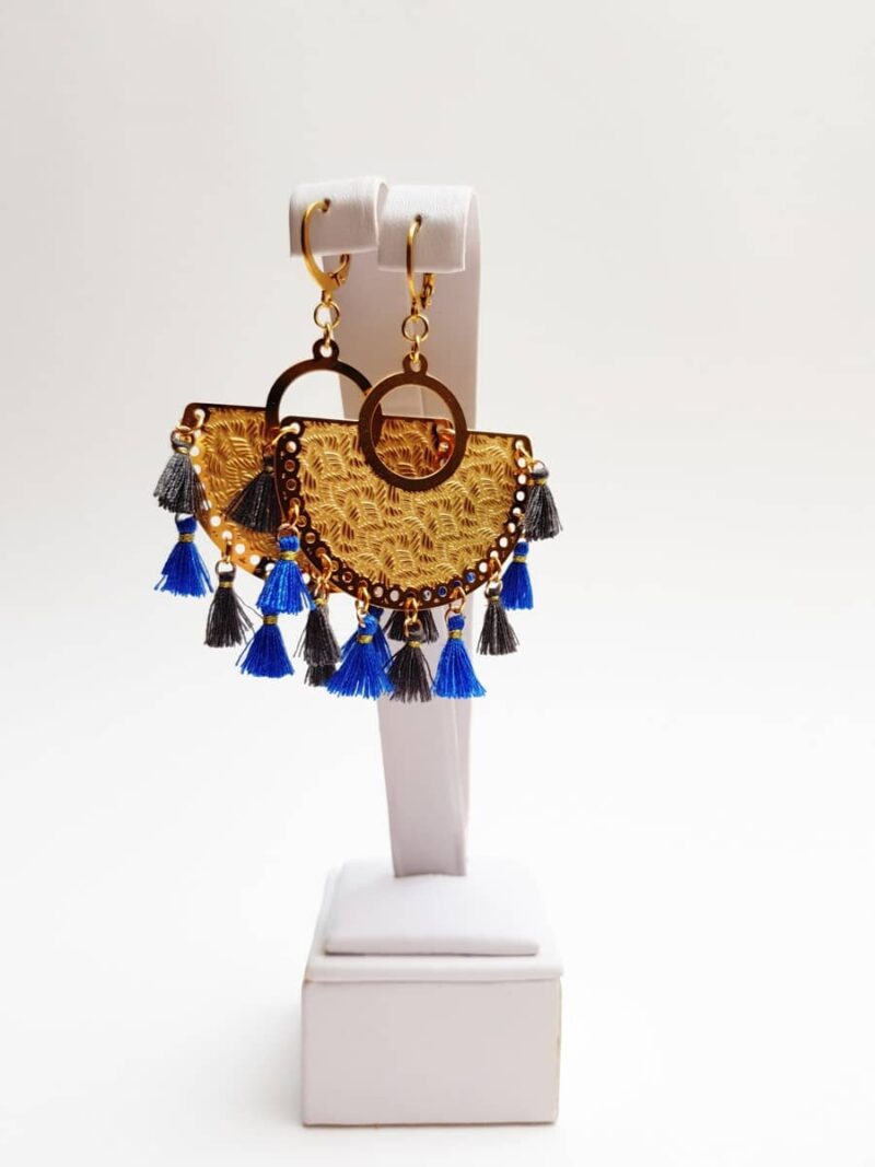 Kolczyki w stylu Bollywood jak sama nazwa wskazuje inspirowane są stylem znanym z indyjskich filmów. Baza w kolorze złotym jest ozdobiona delikatnymi wytłoczeniami z motywami geometrycznymi i florystycznymi. Do niej dołączone są miniaturowe kobaltowo-szare chwosty, dzięki którym całokształt przypomina biżuterię rodem z bollywood.