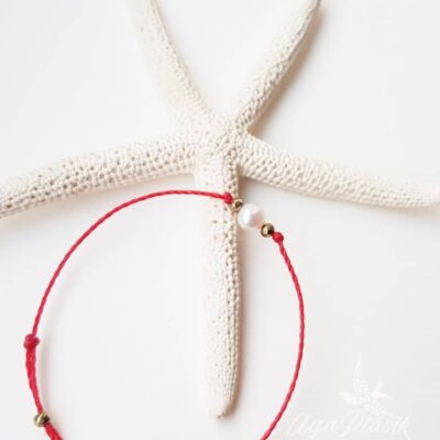 Bransoletka na czerwonym sznurku z perłą słodkowodną i złotymi hematytami.