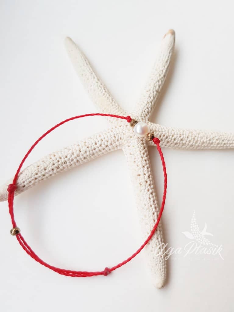 Bransoletka na czerwonym sznurku z perłą słodkowodną i złotymi hematytami.