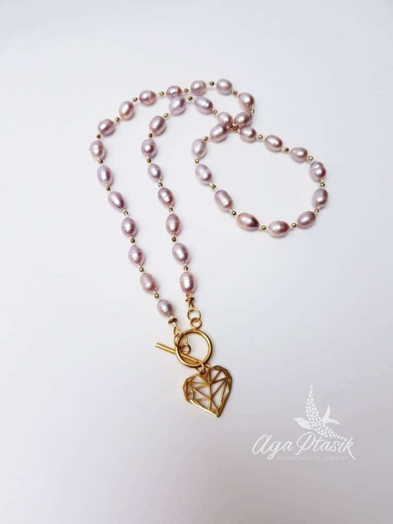 Naszyjnik z różowych pereł o wydłużonym kształcie pereł hodowlanych przekładany małymi kuleczkami złotego hematytu z zawieszką w kształcie serca.