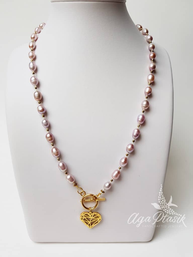 Naszyjnik z różowych pereł o wydłużonym kształcie pereł hodowlanych przekładany małymi kuleczkami złotego hematytu z zawieszką w kształcie serca.