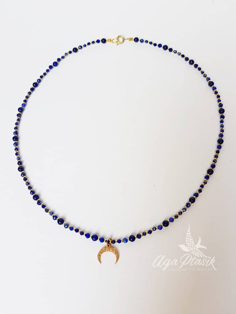 Naszyjnik wykonany z kuleczek lapis lazuli i zawieszki w kolorze złotym w kształcie lunuli.