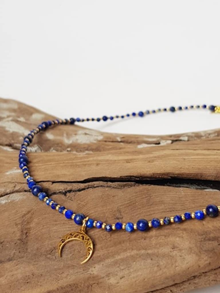 Naszyjnik wykonany z kuleczek lapis lazuli i zawieszki w kolorze złotym w kształcie lunuli.