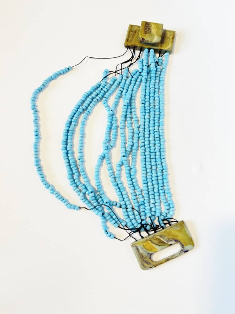 Afrykańska bransoleta z niebieskich koralików przed naprawą - rozciągnięte gumki.
