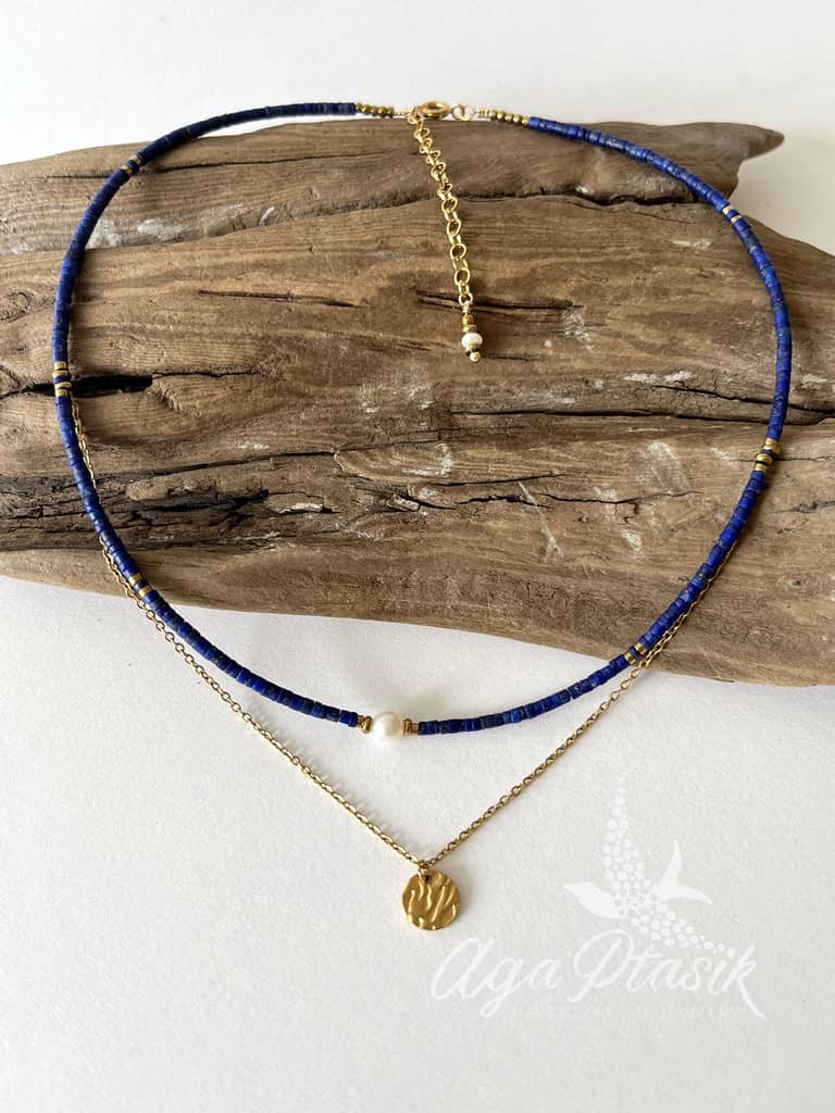 Naszyjnik układający się warstwowo wykonany z kamieni lapis lazuli, i perły oraz łańcuszka z okrągłą zawieszką.